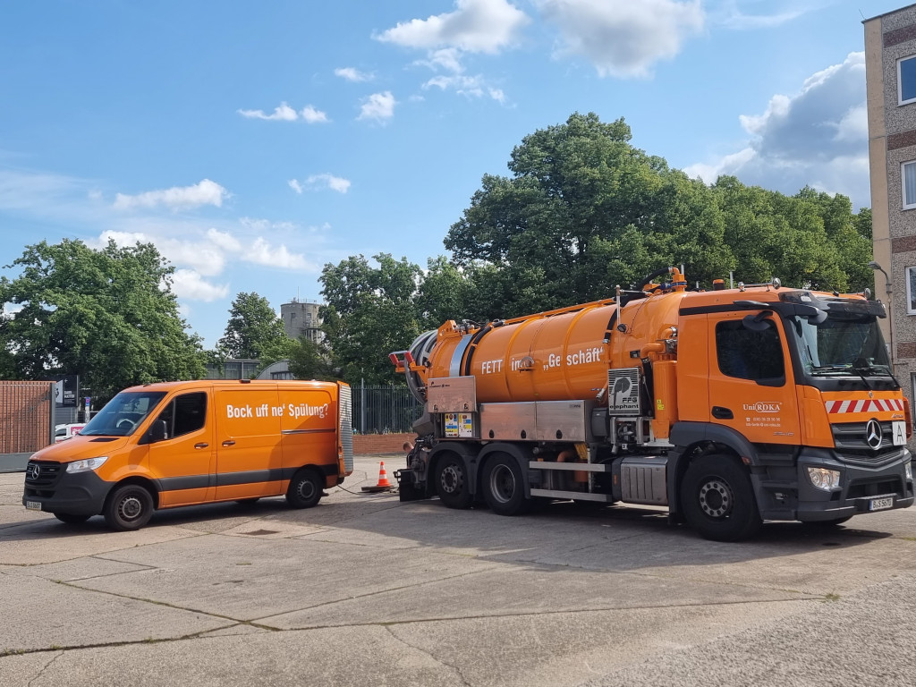 Zu sehen ist ein Reinigungs-LKW der Firma Uni Roka Berlin, daneben steht ein kleines Reinigungsfahrzeug, Fettabscheider Reinigung
